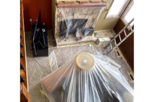 image of interior being painted with plastic covering the furniture